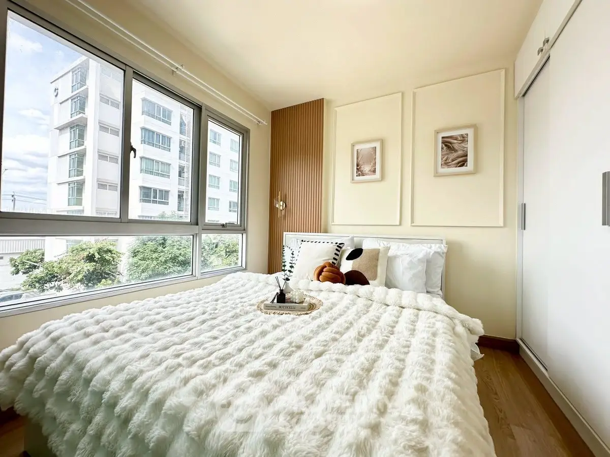 Bright and cozy bedroom with large window and plush bedding in modern apartment.