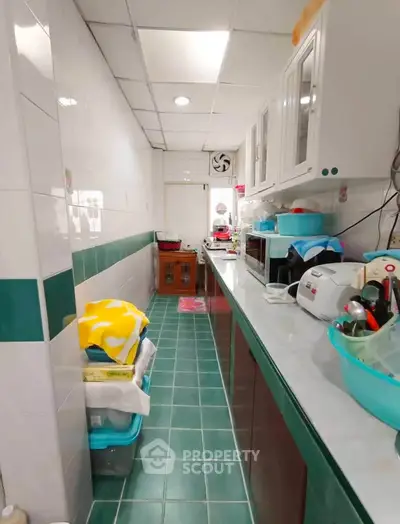 Charming kitchen with closed layout and modern appliances, featuring vibrant green tiles and ample storage space.