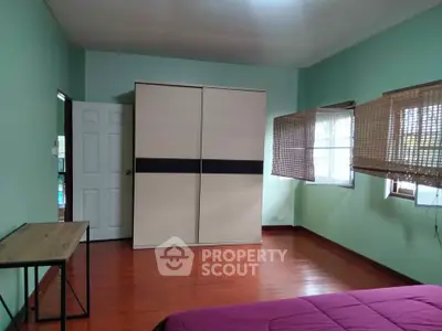 Spacious bedroom with wooden flooring and large wardrobe in a cozy home.