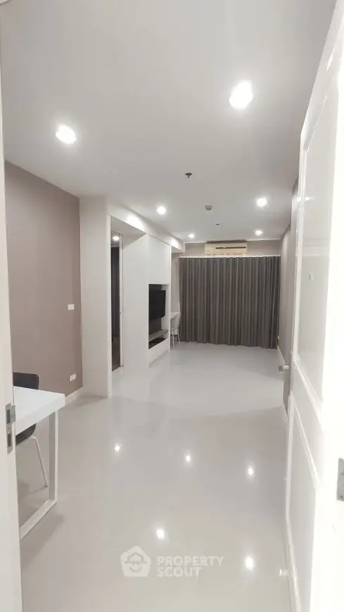 Modern living room with sleek design and ample lighting, featuring a TV and elegant curtains.