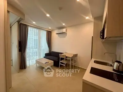 Modern living room with open kitchen, featuring sleek furniture and ample natural light.