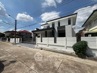 Modern two-story house with sleek design and spacious driveway in a suburban neighborhood.