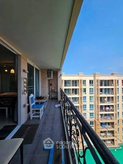 Spacious balcony with stunning view of modern apartment complex and pool.