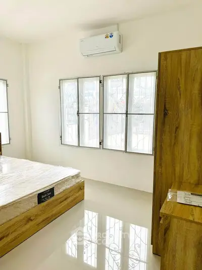 Bright bedroom with modern wooden furniture and air conditioning unit.