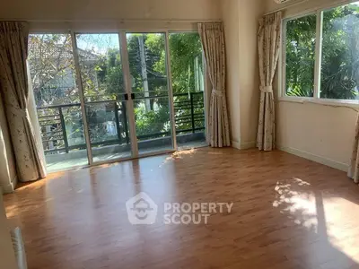 Spacious sunlit room with large windows and balcony access
