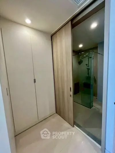 Modern bathroom with glass shower and sleek storage cabinets in a contemporary apartment.