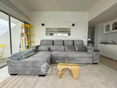 Spacious living room with modern gray sectional sofa and stylish glass coffee table.
