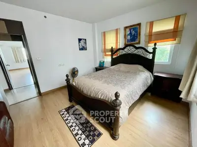 Spacious bedroom with elegant wooden bed and natural light in modern apartment.