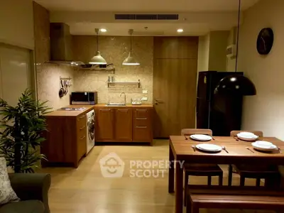 Modern kitchen with dining area featuring wooden cabinets and sleek appliances.