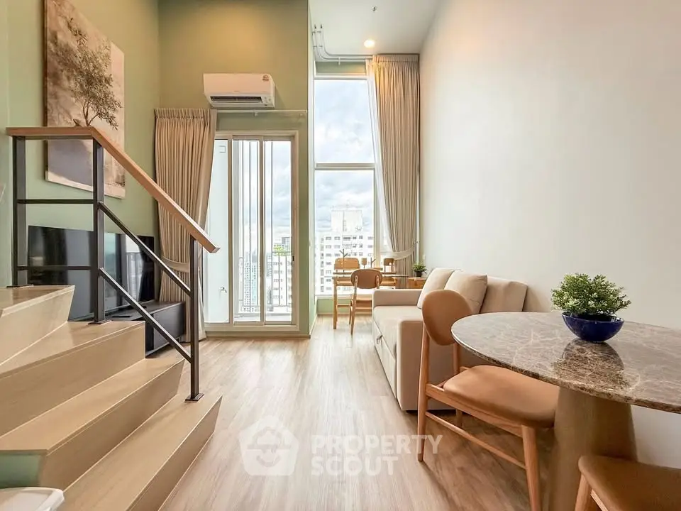 Modern duplex living room with high ceilings and large windows offering city views.