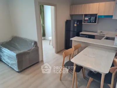 Modern apartment interior with kitchen and living area, featuring sleek furniture and appliances.