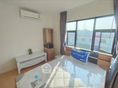 Bright bedroom with large windows and modern furnishings in urban apartment.