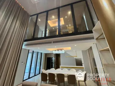 Luxurious duplex apartment with high ceiling and modern chandelier, featuring an elegant dining area and a cozy upper-level loft space.