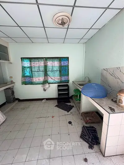 Spacious kitchen with tiled floor and ample natural light, featuring a closed layout and potential for customization.