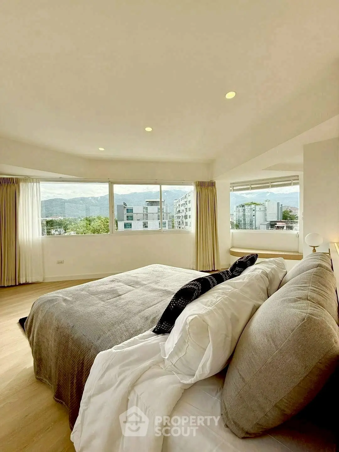Spacious bedroom with panoramic windows offering stunning city and mountain views.