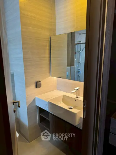 Modern bathroom with sleek sink and large mirror in contemporary apartment.