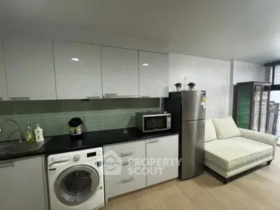 Modern kitchen with sleek cabinets, washing machine, and cozy seating area.
