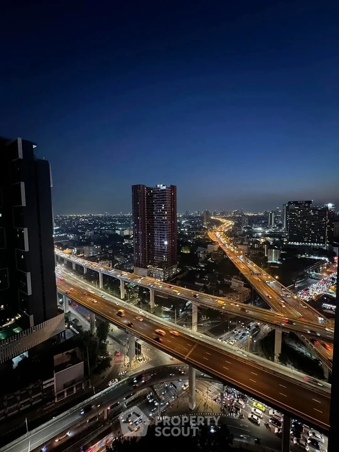 Stunning cityscape view from high-rise building at night with illuminated highways and skyline.