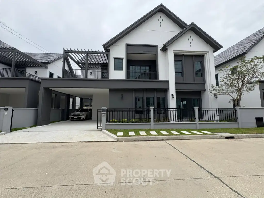 Modern two-story house with sleek design and spacious driveway in a suburban neighborhood.