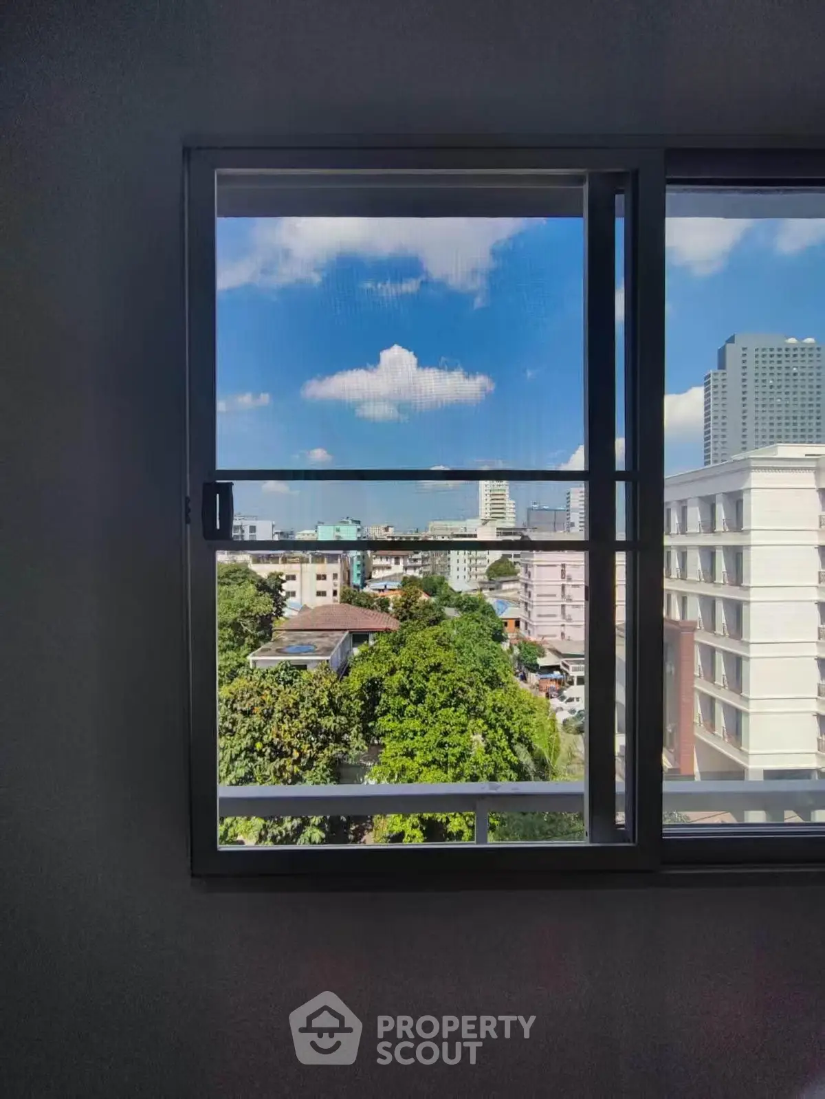 Stunning cityscape view from a modern apartment window, showcasing urban skyline and lush greenery.