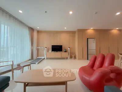 Spacious modern living room with unique red chair and treadmill, perfect for relaxation and fitness.