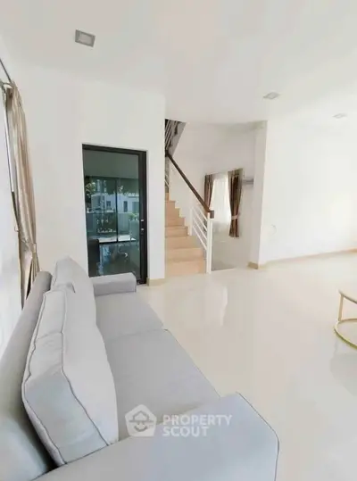 Spacious modern living room with elegant staircase and cozy sofa