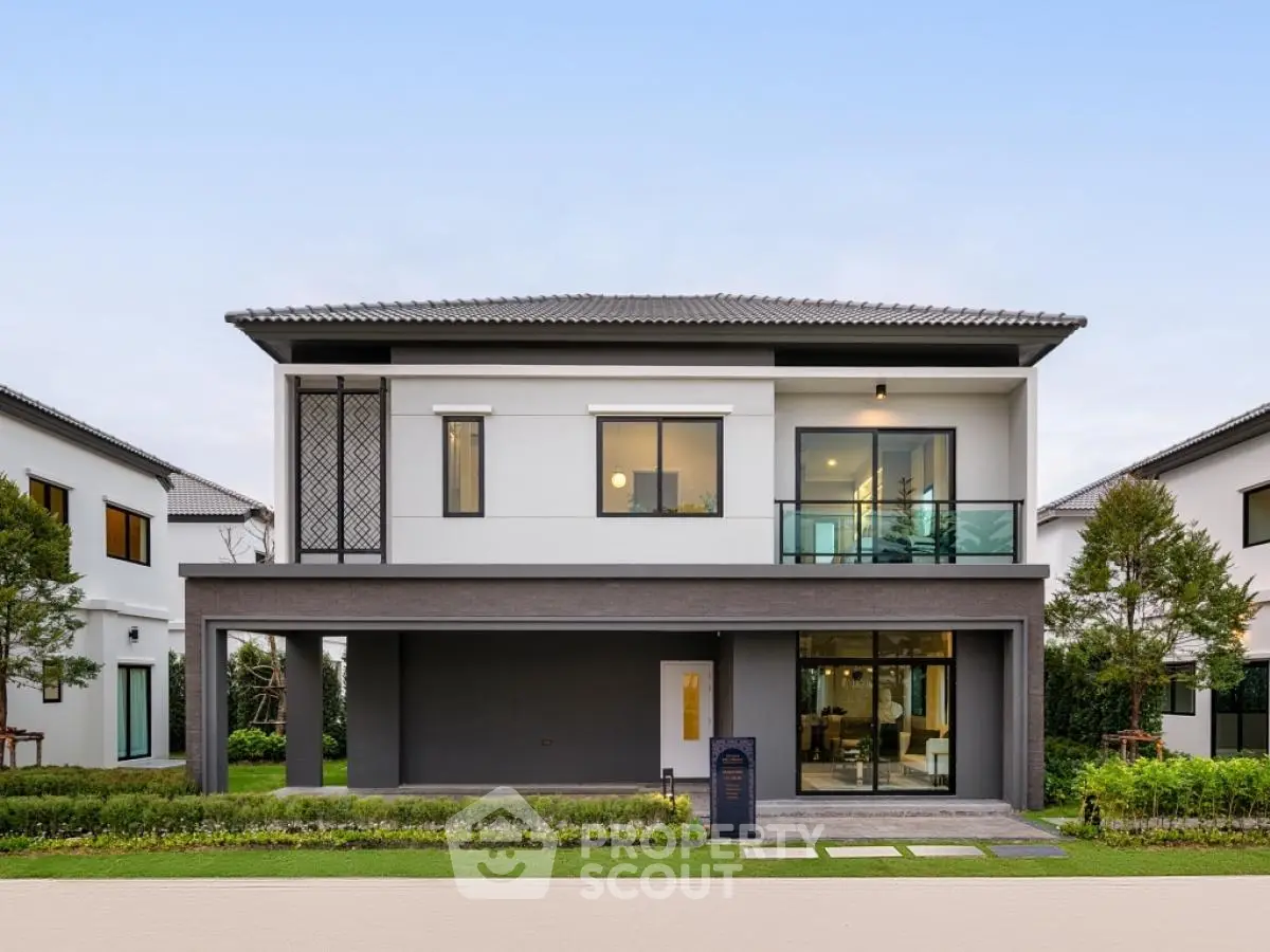 Modern two-story house with large windows and manicured lawn in a suburban neighborhood.