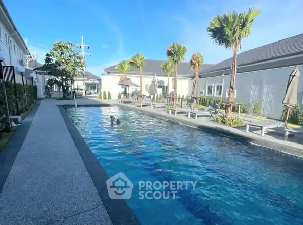 Luxurious residential pool area with palm trees and modern design, perfect for relaxation and leisure.