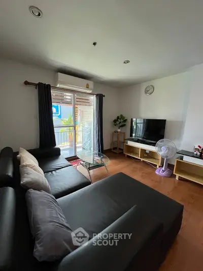 Cozy living room with modern sofa and entertainment setup, featuring a balcony view.