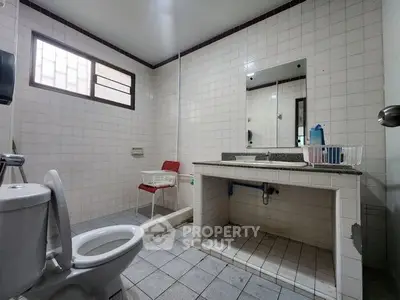 Spacious bathroom with tiled walls, large mirror, and modern fixtures.