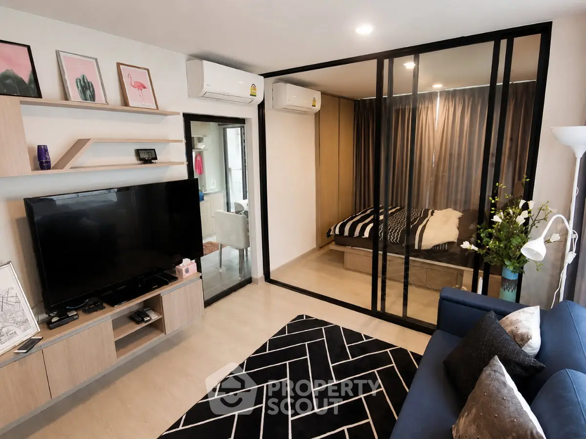 Modern living room with glass partitioned bedroom, stylish decor, and sleek furniture.