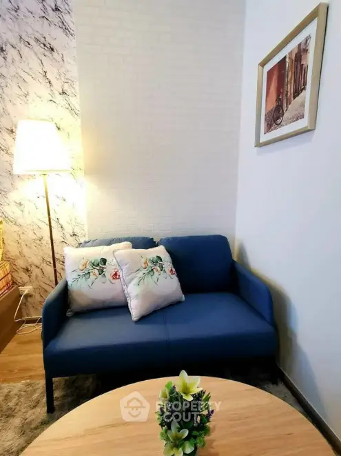 Cozy living room corner with blue sofa and decorative pillows, perfect for relaxation.