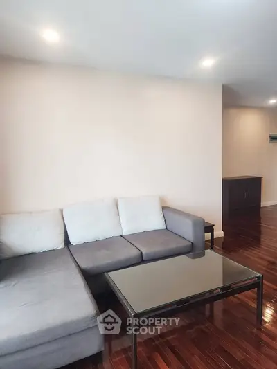 Spacious living room with modern sectional sofa and sleek wooden flooring.