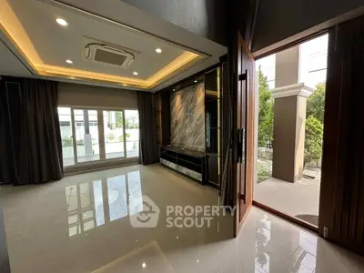 Spacious modern living room with large windows and elegant lighting, opening to a lush garden view.