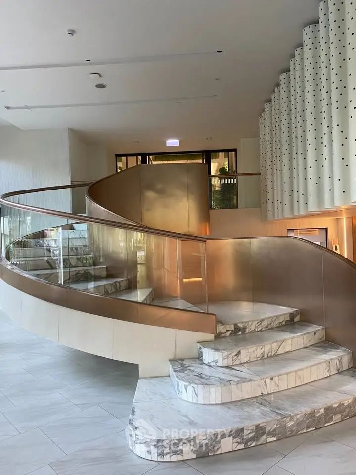 Luxurious spiral staircase with marble steps and elegant design in modern building entrance.