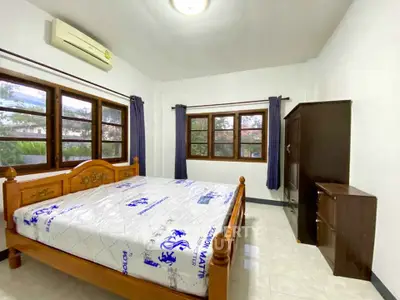 Spacious bedroom with large windows and wooden furniture in a cozy home.