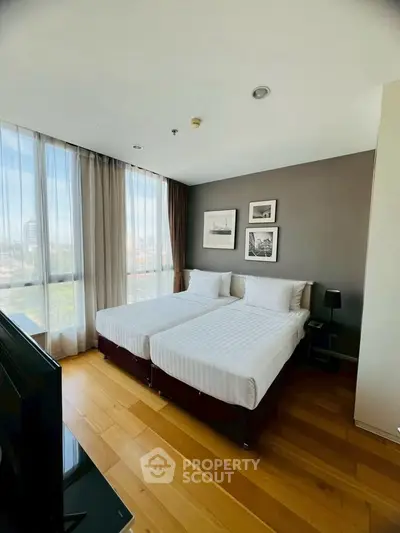 Modern bedroom with twin beds, large window, and stylish decor in a high-rise apartment.