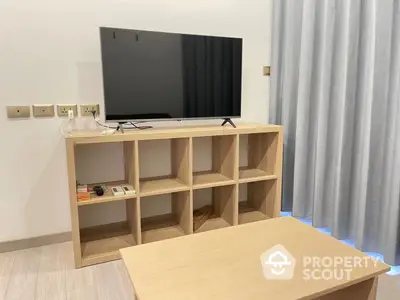 Modern minimalist living room with a sleek flat-screen TV on a wooden console, complemented by soft gray curtains and a matching coffee table.