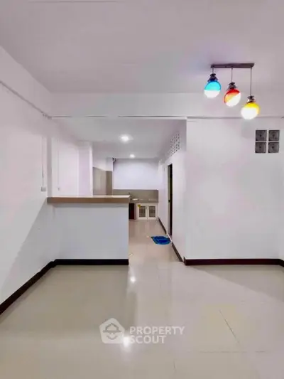 Spacious open-plan living area with modern lighting and sleek kitchen counter.