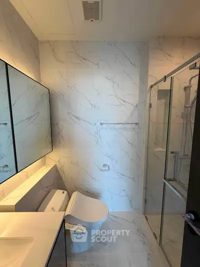 Modern bathroom with marble tiles and glass shower enclosure