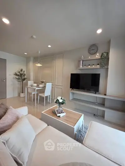 Modern living room with stylish decor and open dining area, featuring a cozy sofa and sleek TV setup.