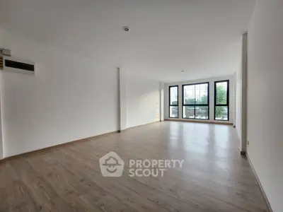 Spacious empty living room with large windows and wooden flooring, ideal for customization.