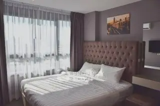 Cozy bedroom with large window and stylish decor in modern apartment.