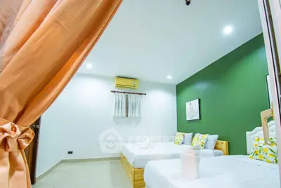 Bright and cozy bedroom with twin beds and green accent wall