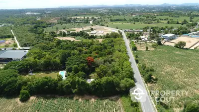 Expansive aerial view of lush green land with road access, ideal for development opportunities.