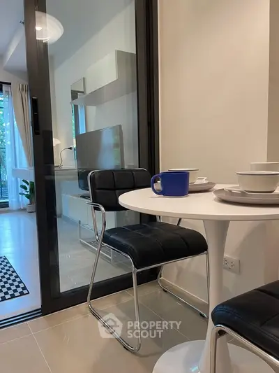 Modern dining area with sleek black chairs and a round table, open layout to a stylish kitchen.