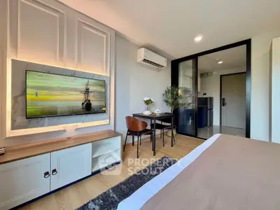 Modern studio apartment with stylish decor, featuring a wall-mounted TV, dining area, and air conditioning.