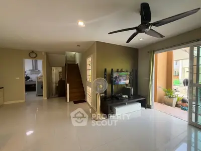 Spacious living room with modern ceiling fan and open layout, leading to outdoor patio area.
