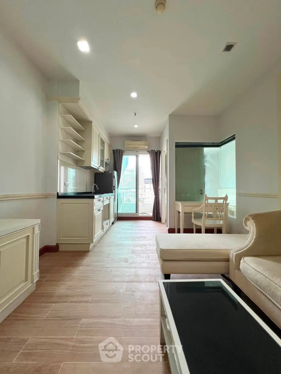 Spacious living room with modern open kitchen and balcony view in a stylish apartment.