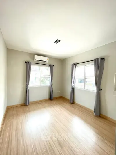 Bright and airy bedroom with wooden flooring and large windows in modern home.